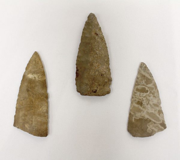 Three old looking arrow heads on a white surface