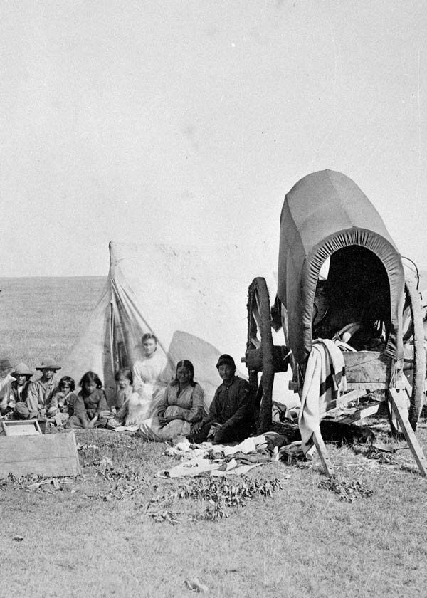 A Metis family camps by their two-wheeled Red River cart