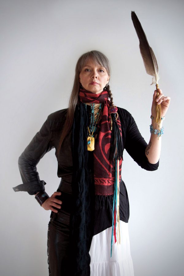 Woman standing with one hand on hip and other holding a large feather