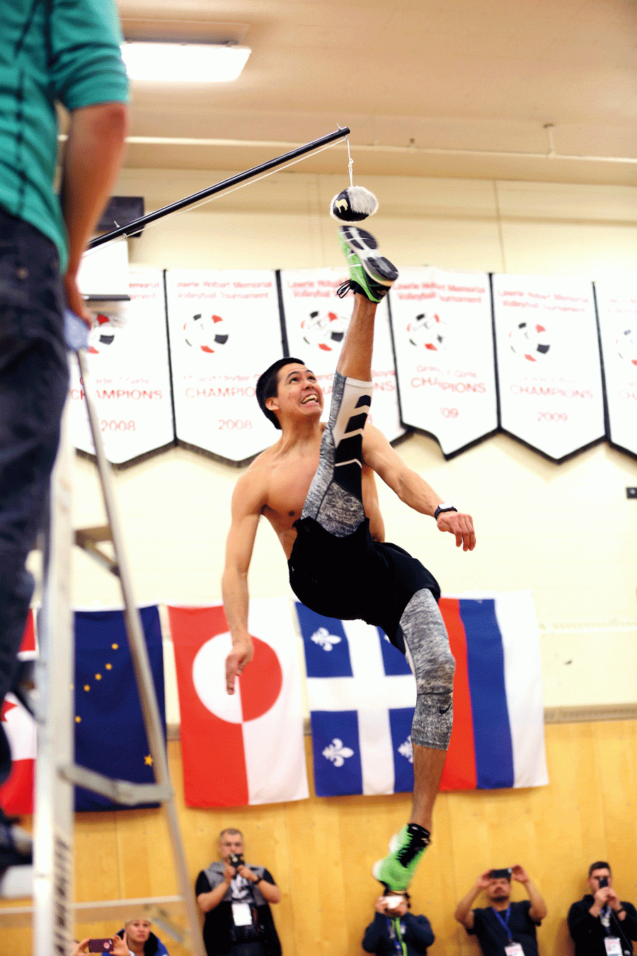 Boy in a gym kicking a ball hanging from a stick