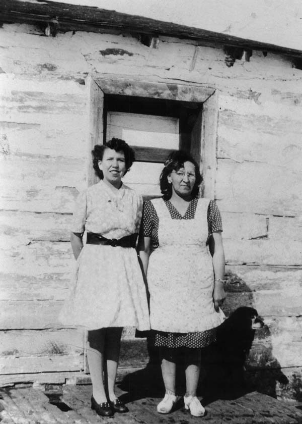 Two women stand in front of a house