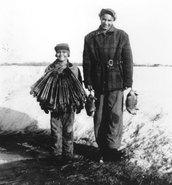 Two people stand with hunting paraphernalia